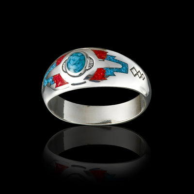 Wolvestuff’s Sleeping Beauty Mountain Ring on a black background, made from sterling silver with a turquoise centre. ocean red coral arrow tips with intricate stamping along the band
